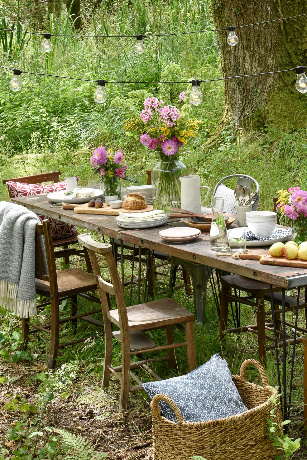 A wild woodland area with a long vintage table and mismatched chairs