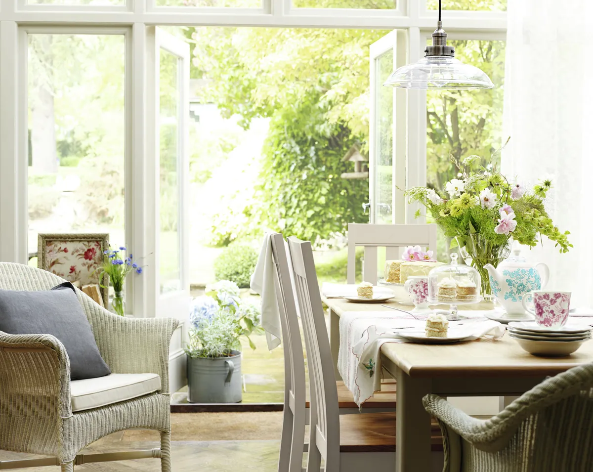 An airy conservatory space with a white dining table and chairs