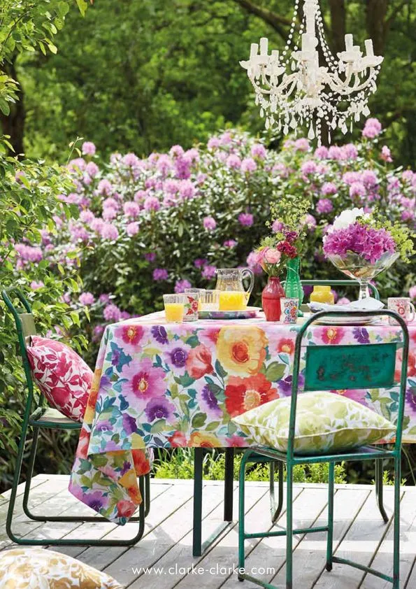 A green metal garden table covered with a bold floral tablecloth