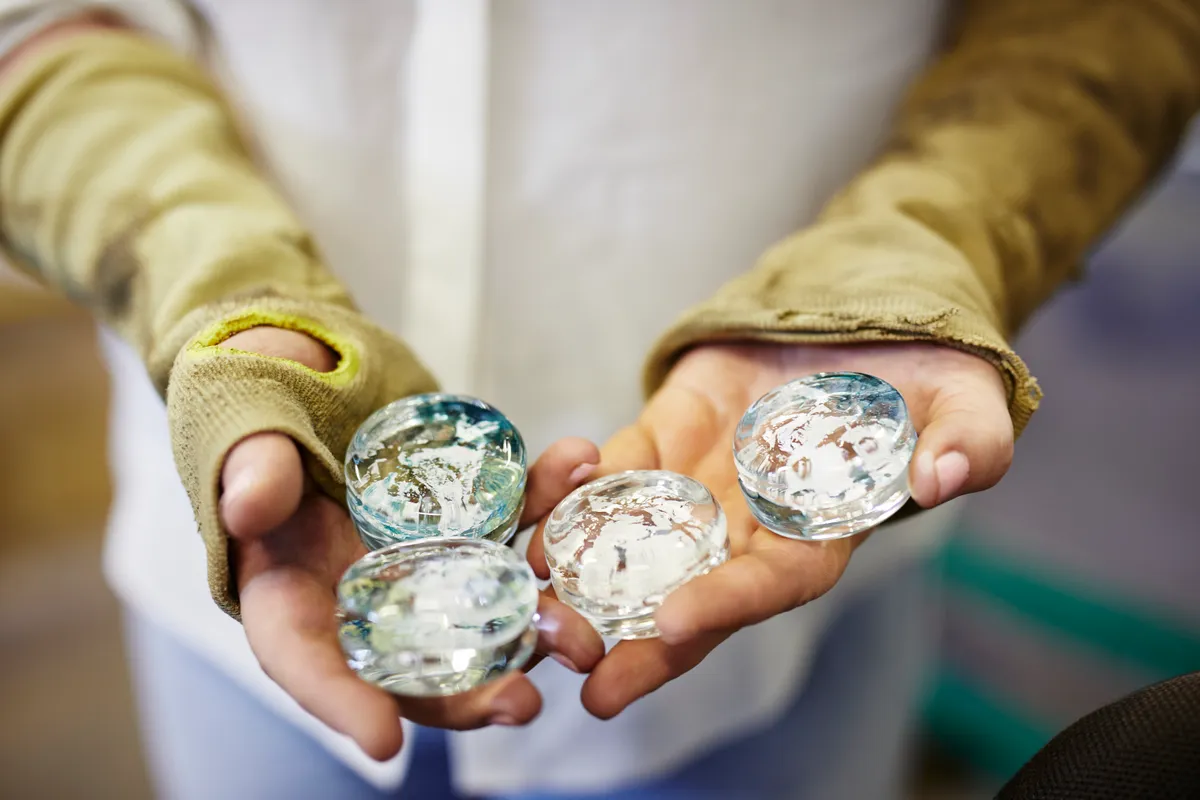 Glassblower Laura Smith holding a selection of her handmade glass drawer pulls