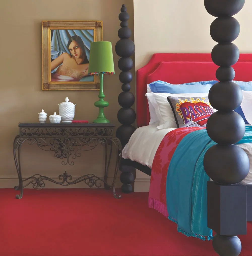A contemporary four poster bed resting on bright red carpet