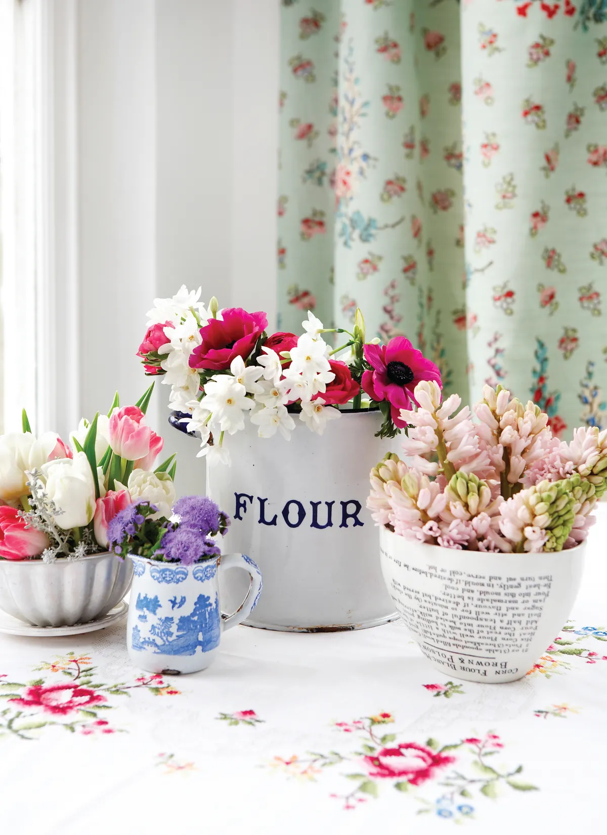 A collection of vintage bowls, vases and jugs filled with spring flowers.