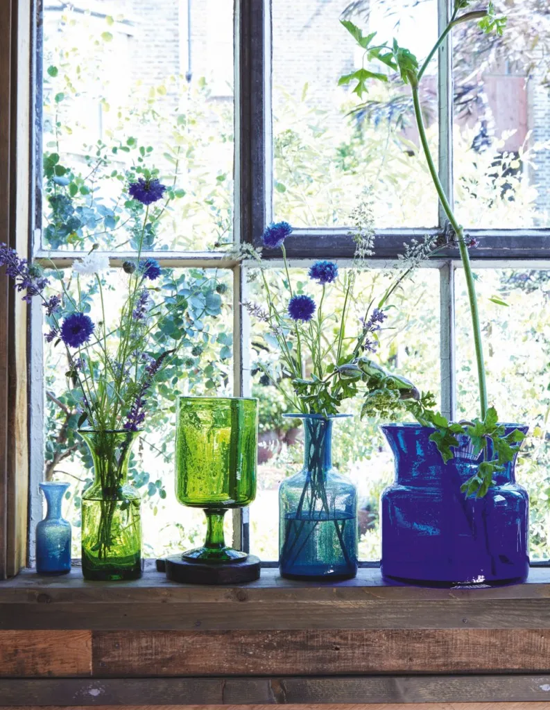 Mid-century Scandinavian Glass Vases filled with tall blue flowers and eucalyptus in front of an open sash window