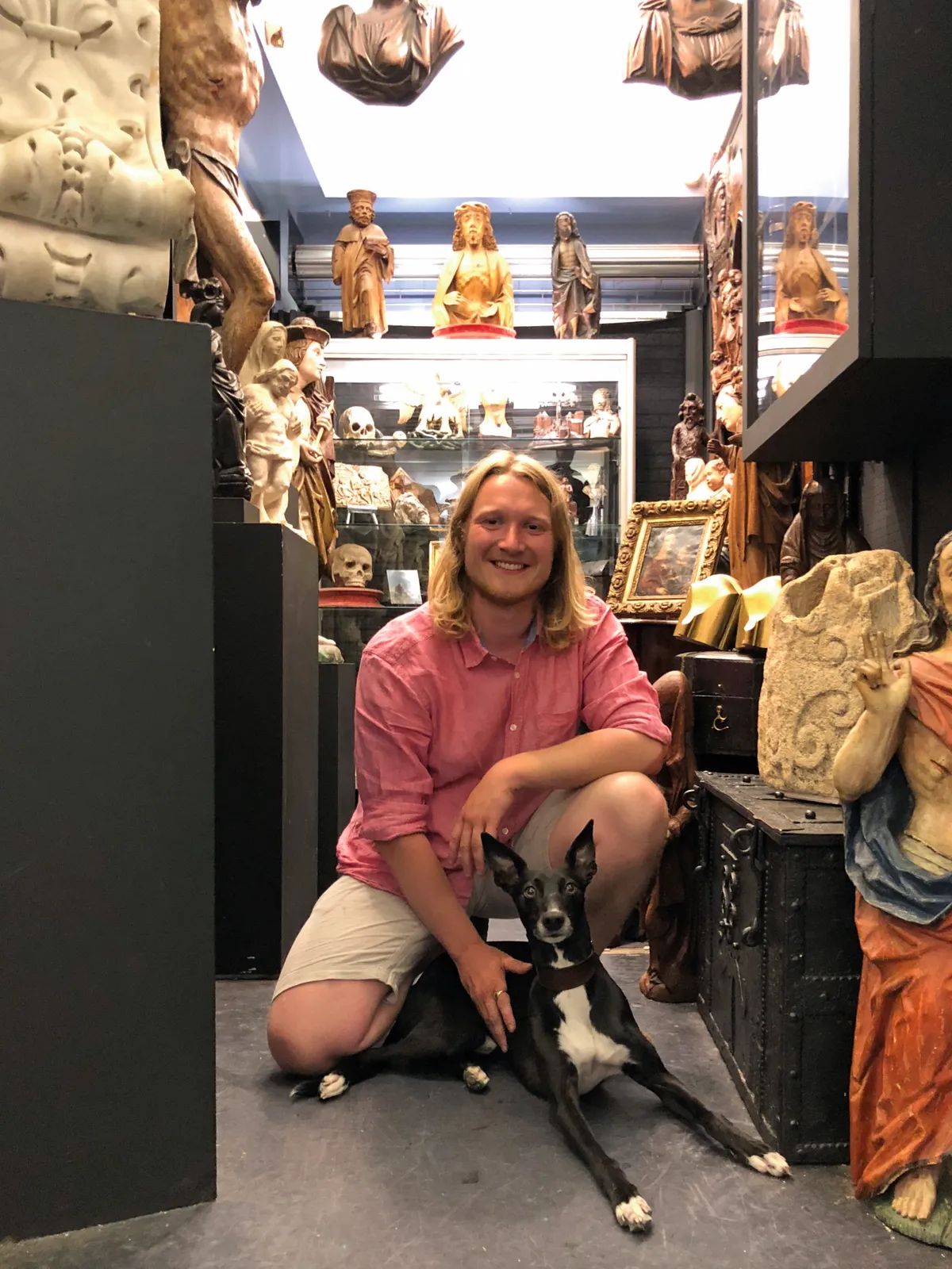 Antiques Dealer Matthew Holder kneeling with his dog in his showroom