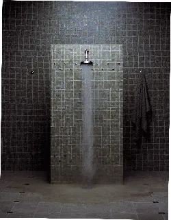 A shower with a dark ceramic wall