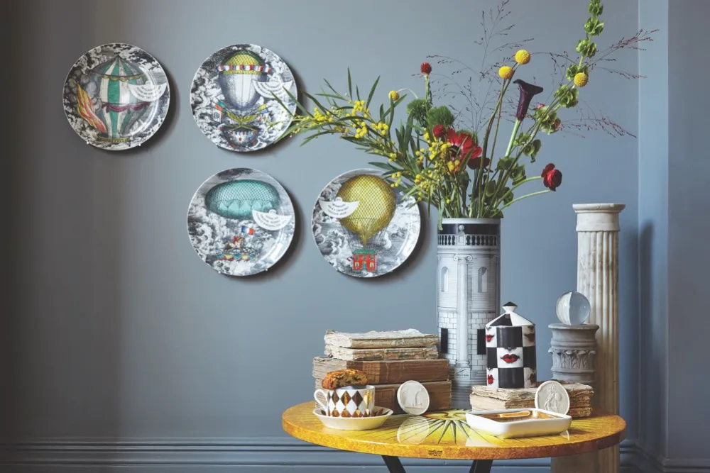 Decorative Fornasetti side plates displayed on a slate-grey wall