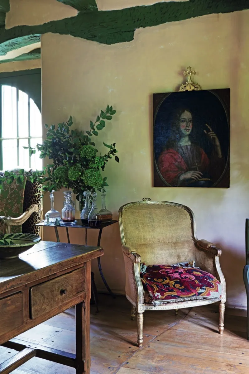 An antique armchair sits underneath a portrait painting