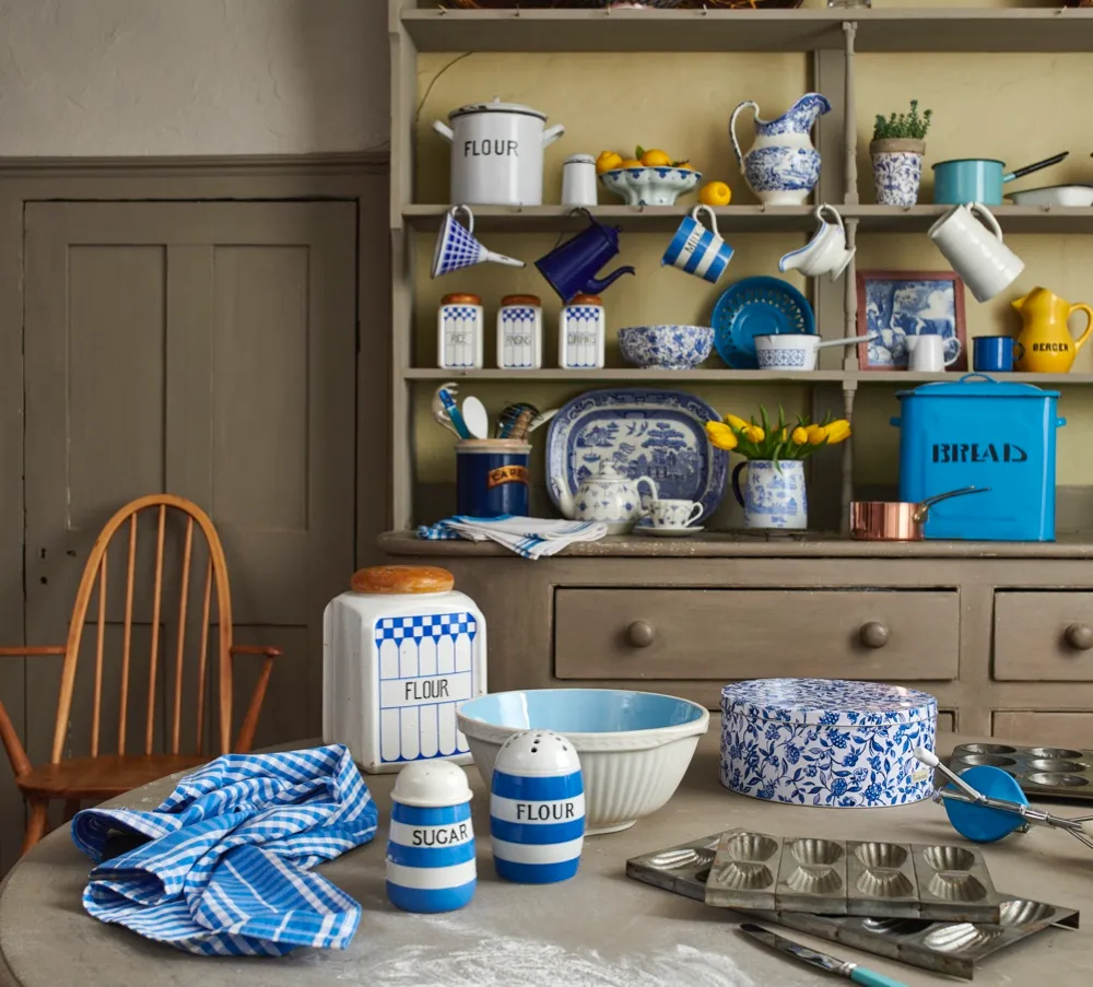 A kitchen dresser and table full of blue and white detailed platters, cups and saucers