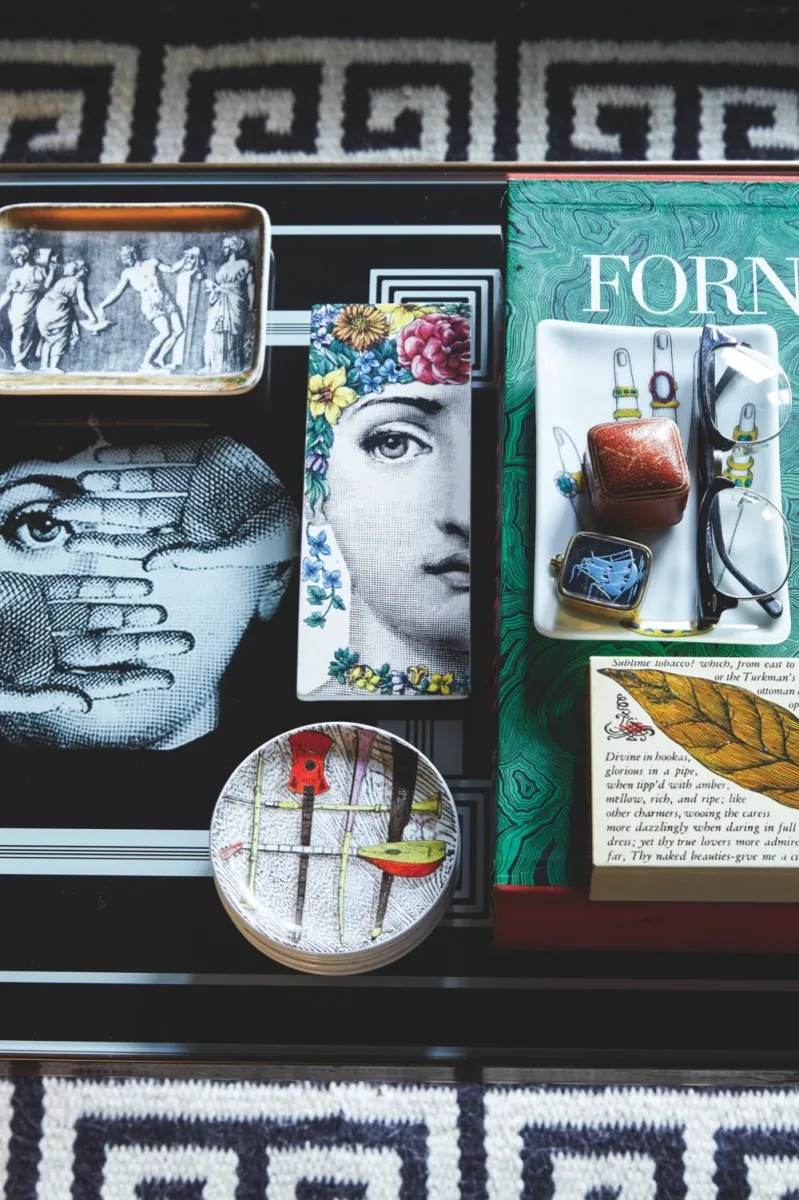A black coffee table peppered with Fornasetti curios