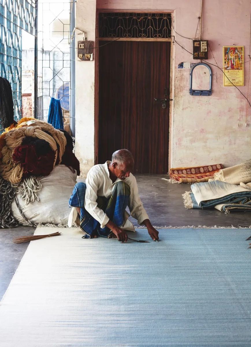 A man working on a flat weave rug