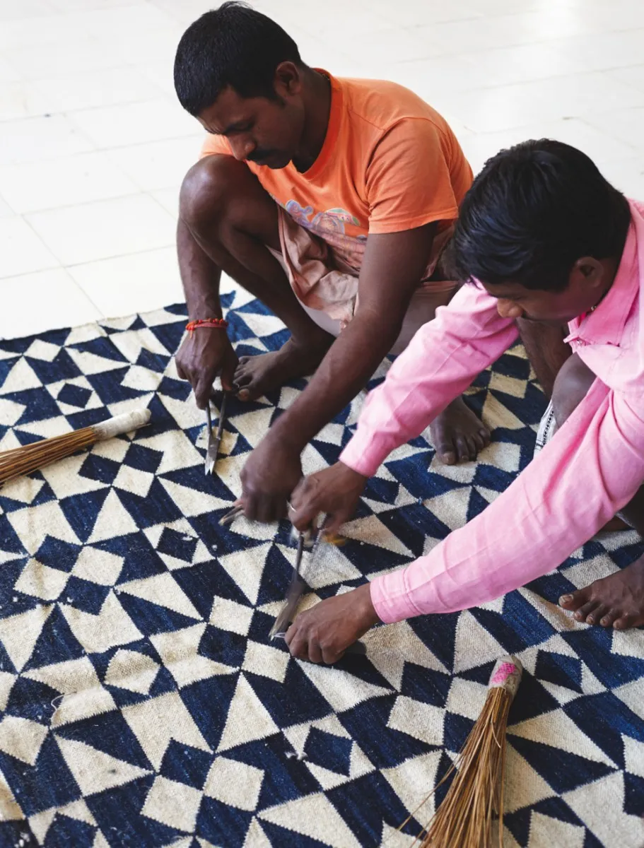 Two men trimming a rug