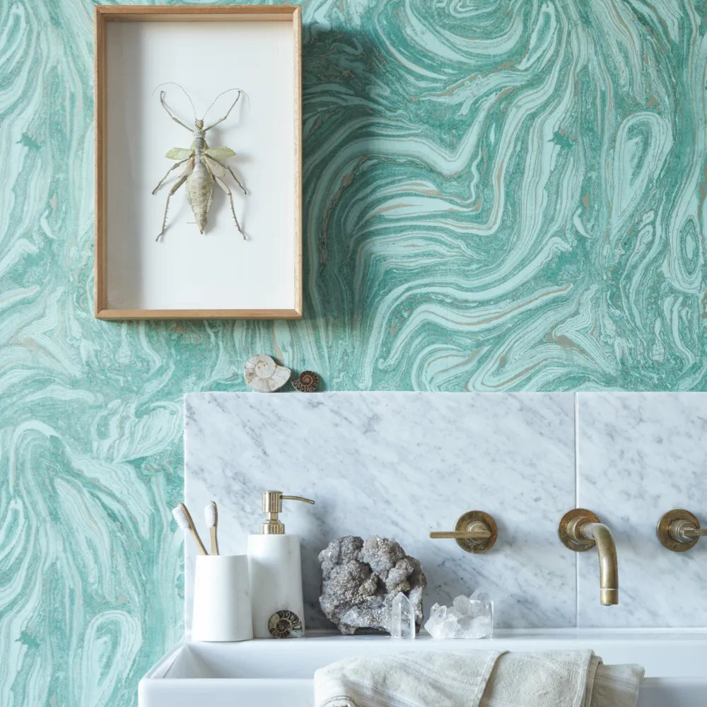 A marble sink decorated with fossils against malachite wallpaper and a framed insect