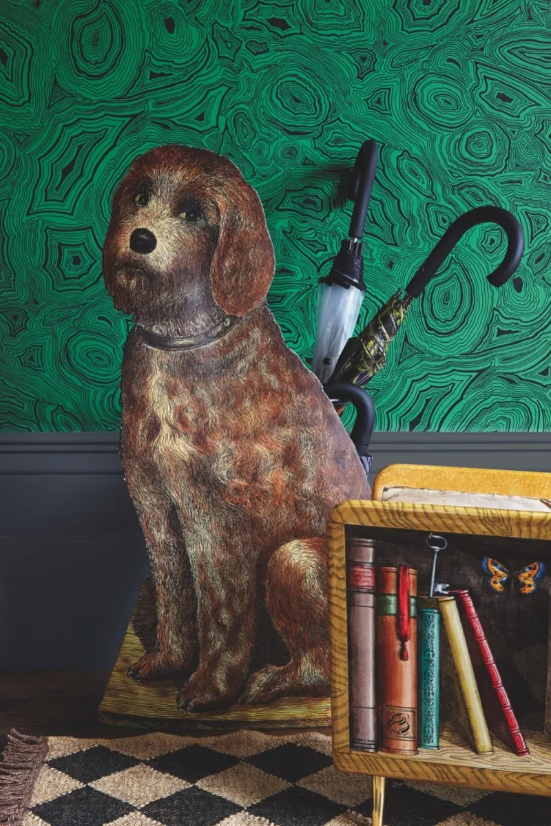 A Fornasetti umbrella stand in the shape of a dog against green malachite wallpaper