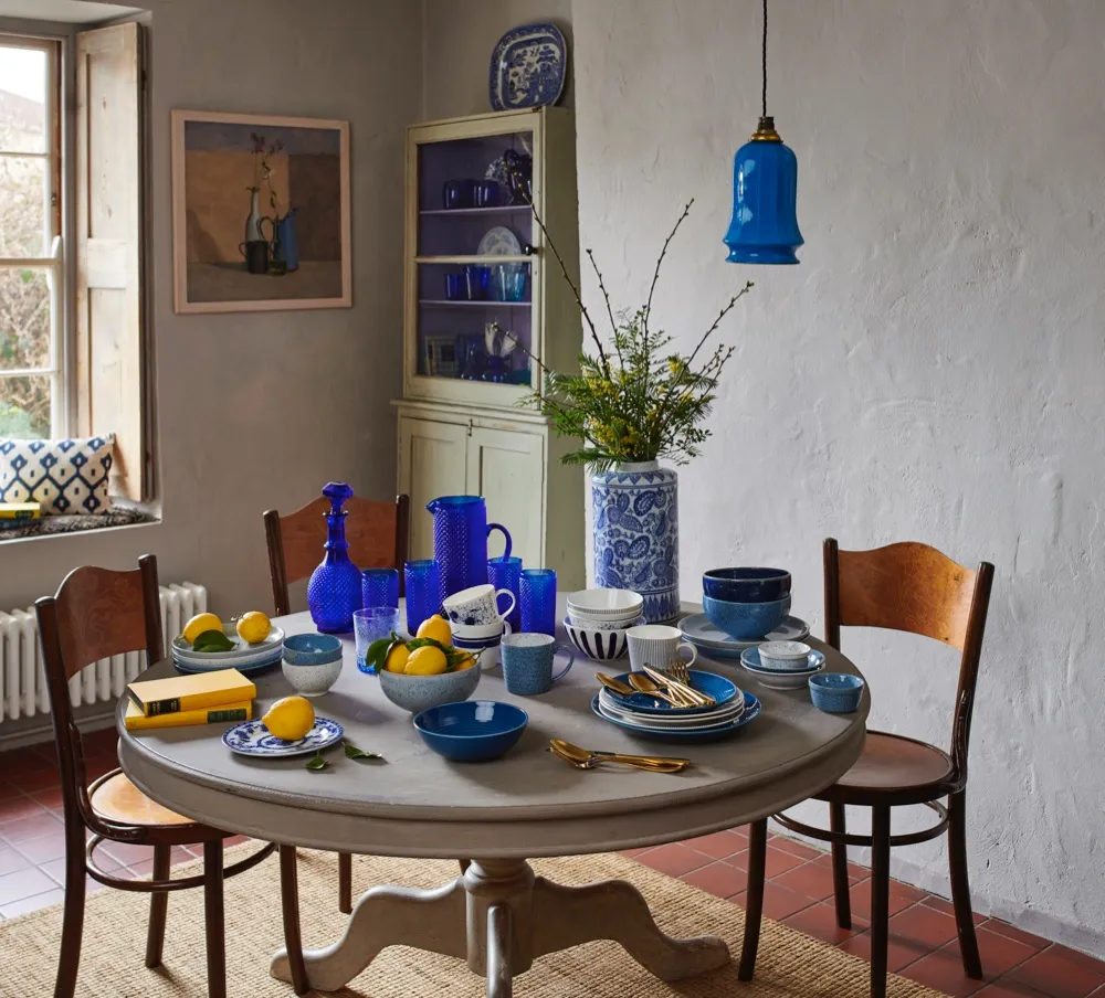 A kitchen table with a collection of blue and white ceramics on it