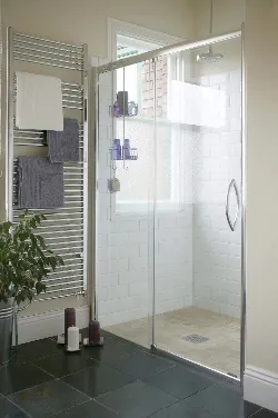 A sleek wetroom with white tiles on the walls of the enclosed shower