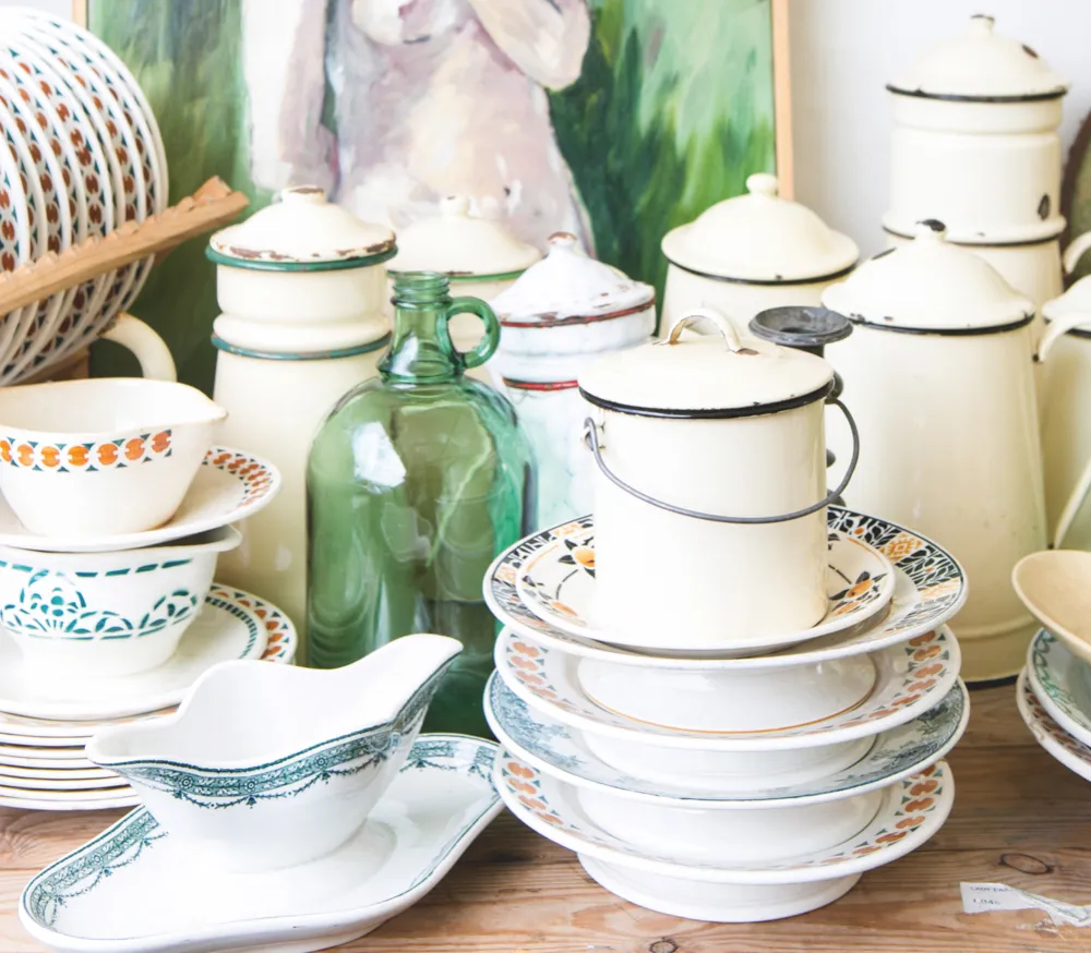 An array of antique enamelware on a table at a flea market