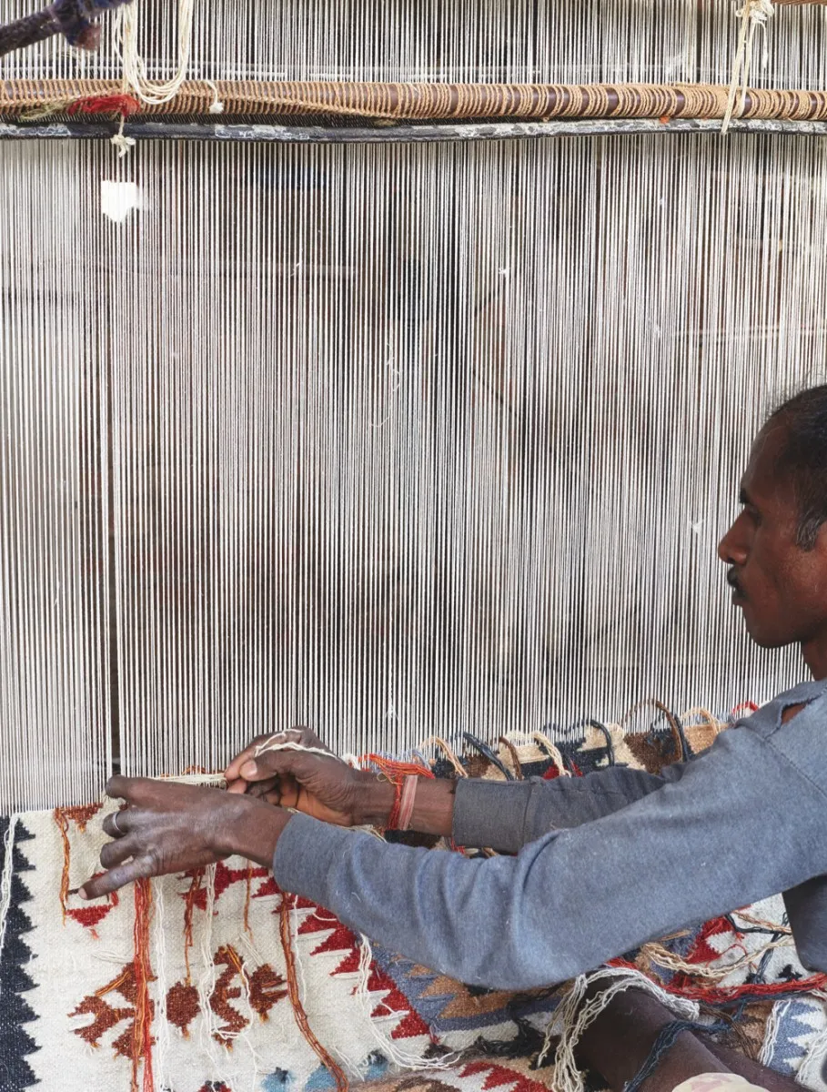 A man weaving the thread horizontally across the vertical thread