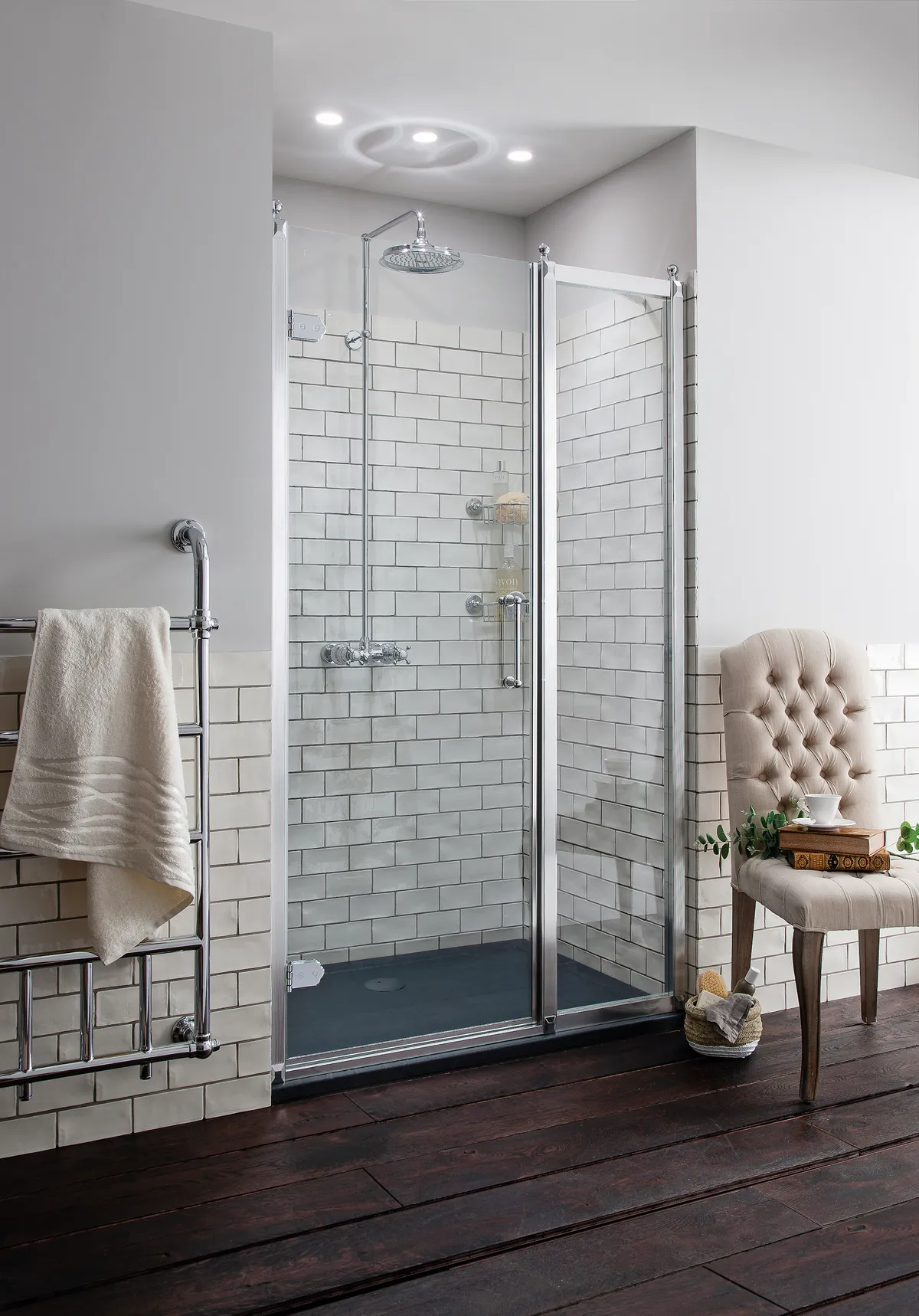 A glass shower enclosure with white metro tiles