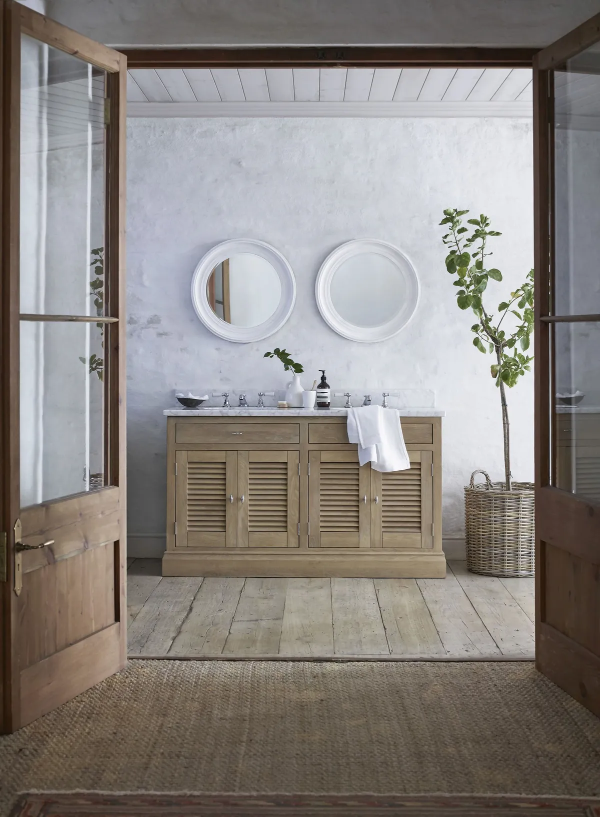 A wooden dresser used as a stand for sinks in a large bathroom