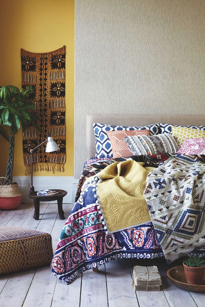 A tribal style quilted bedspread rests on a double bed
