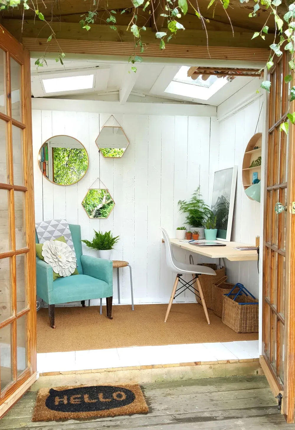 An outdoor office space filled with a teal armchair and a cluster of hexagonal mirrors on the wall