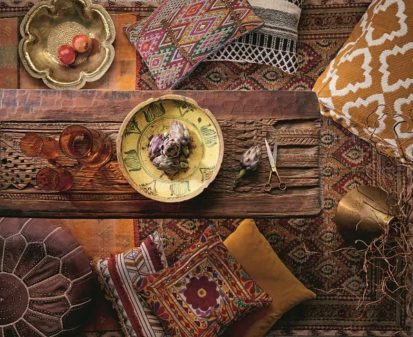A Moroccan-style table surrounded by ornate floor cushions and gold bowls of pomegranates
