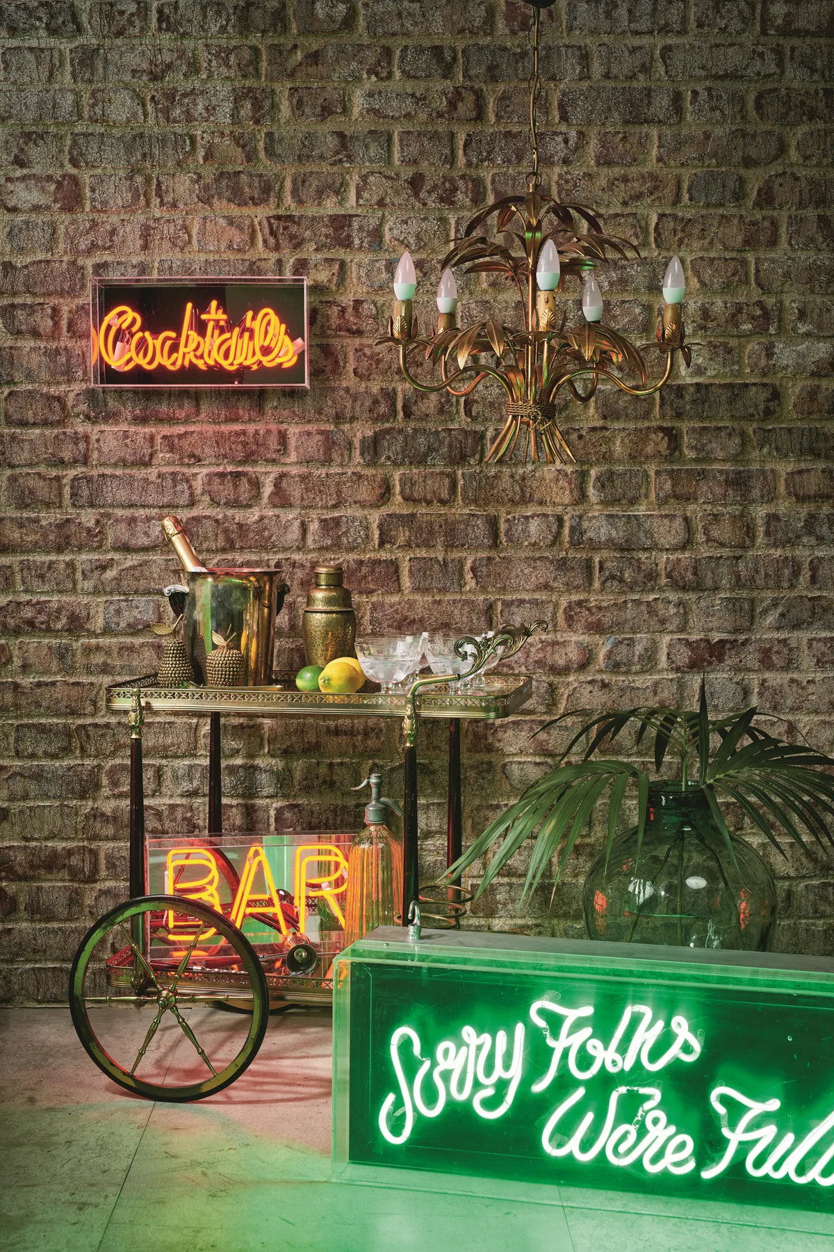 A vintage drinks trolley surrounded by neon lights and decorated with vintage glassware.
