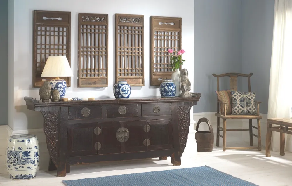 A wide hallway with an oriental-style sideboard flanked by ceramic table lamps and a set of four antique shutters