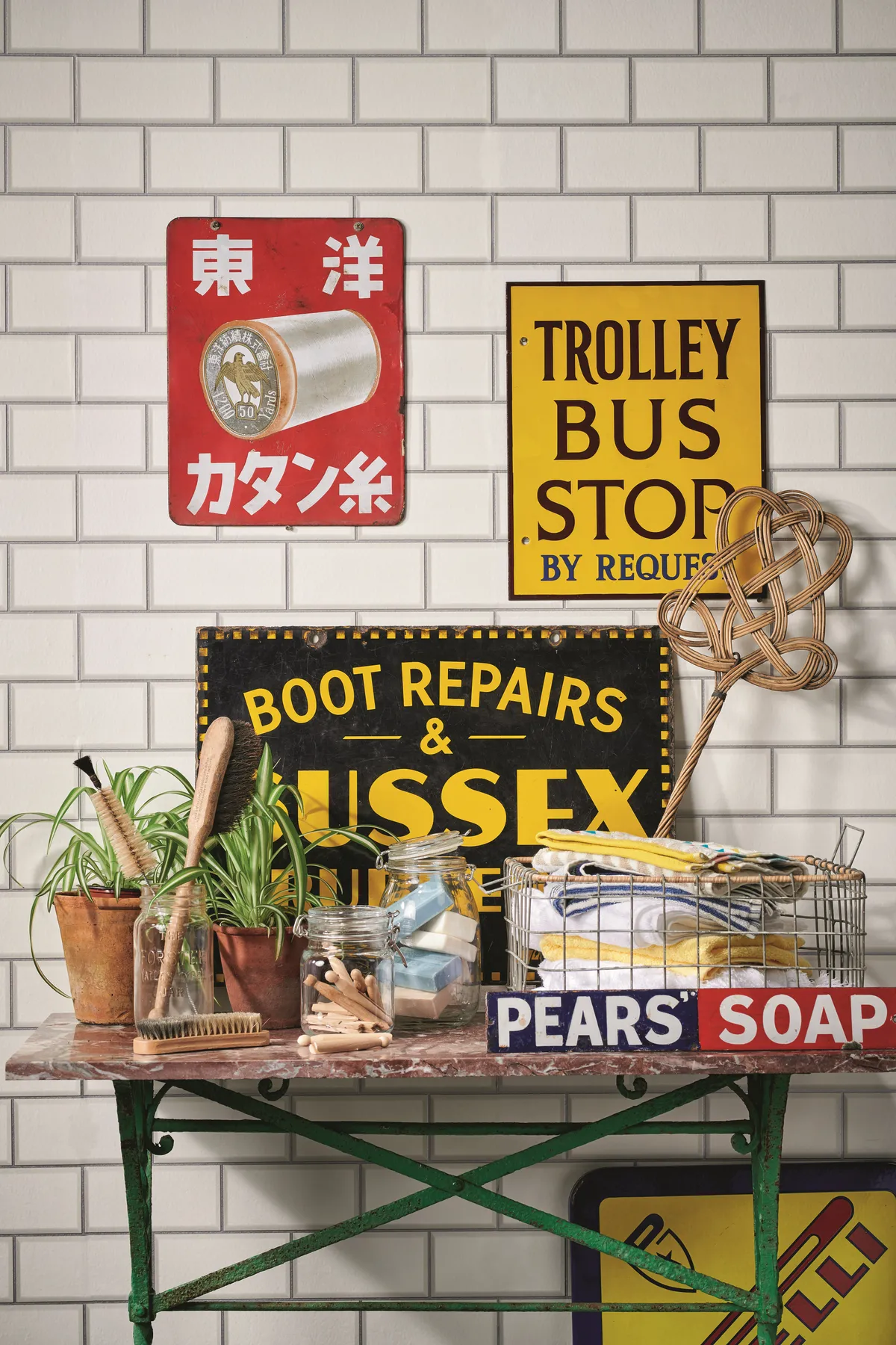An array of vintage signs in a utility room decorated with white metro tiles.