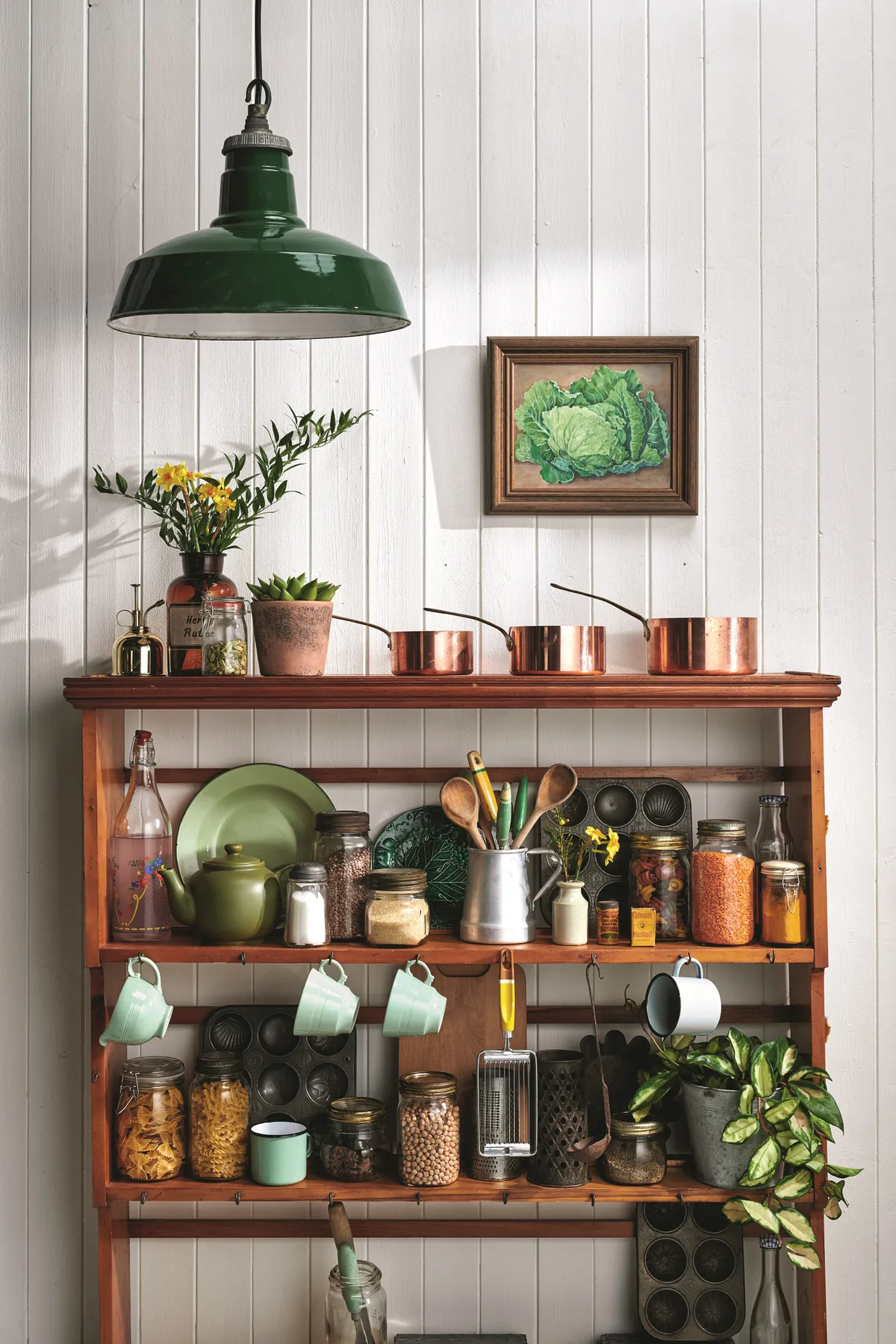 A vintage shelving unit is used to display copper pans and jars of larder essentials in a kitchen.