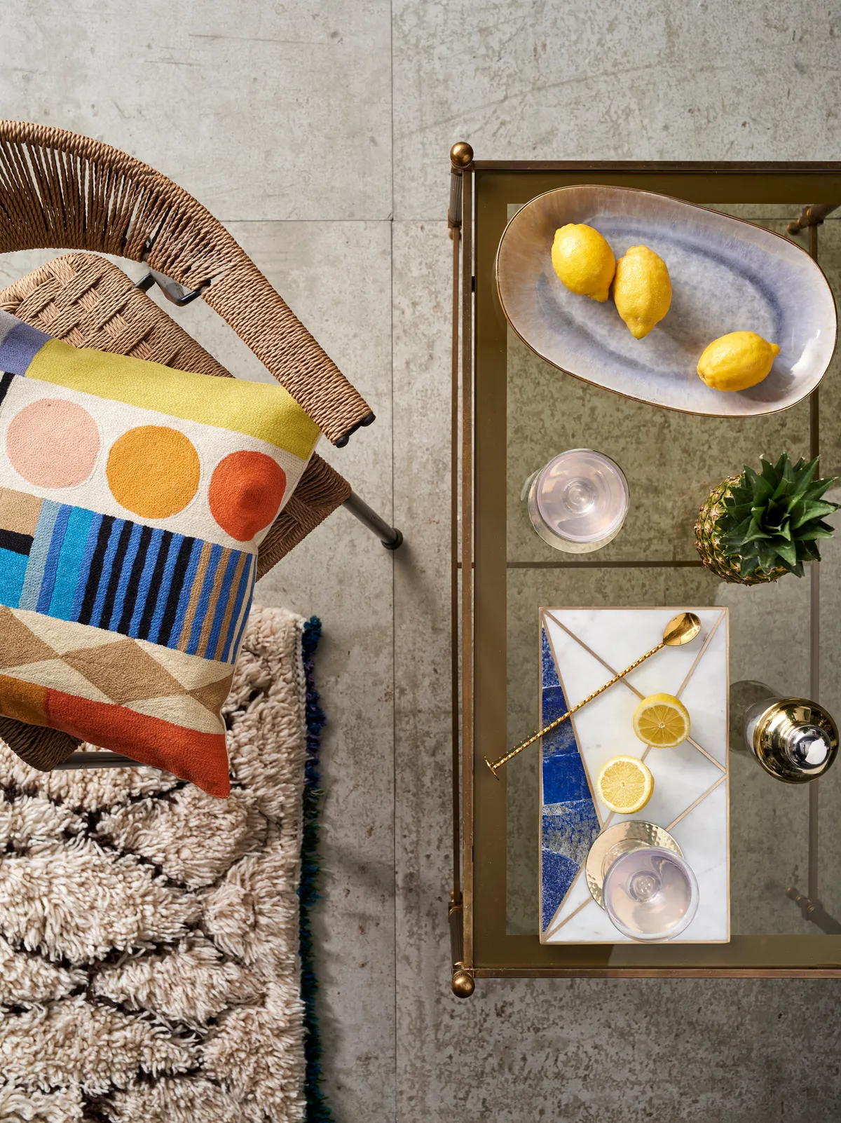A gold and glass coffee table topped with studio ceramics and metallic cocktails accessories