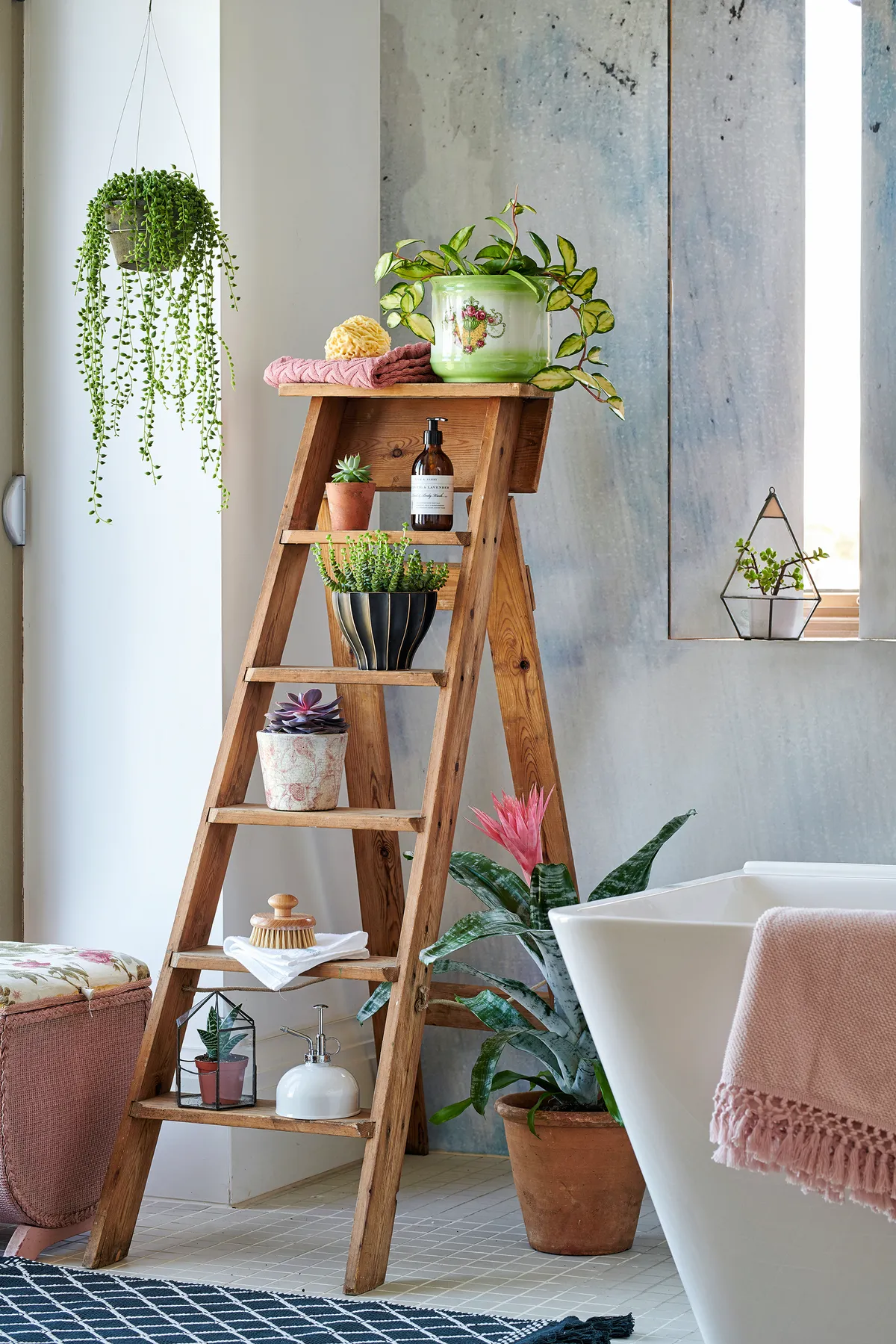 A vintage stepladder used to display small succulents and beauty products in a bathroom.