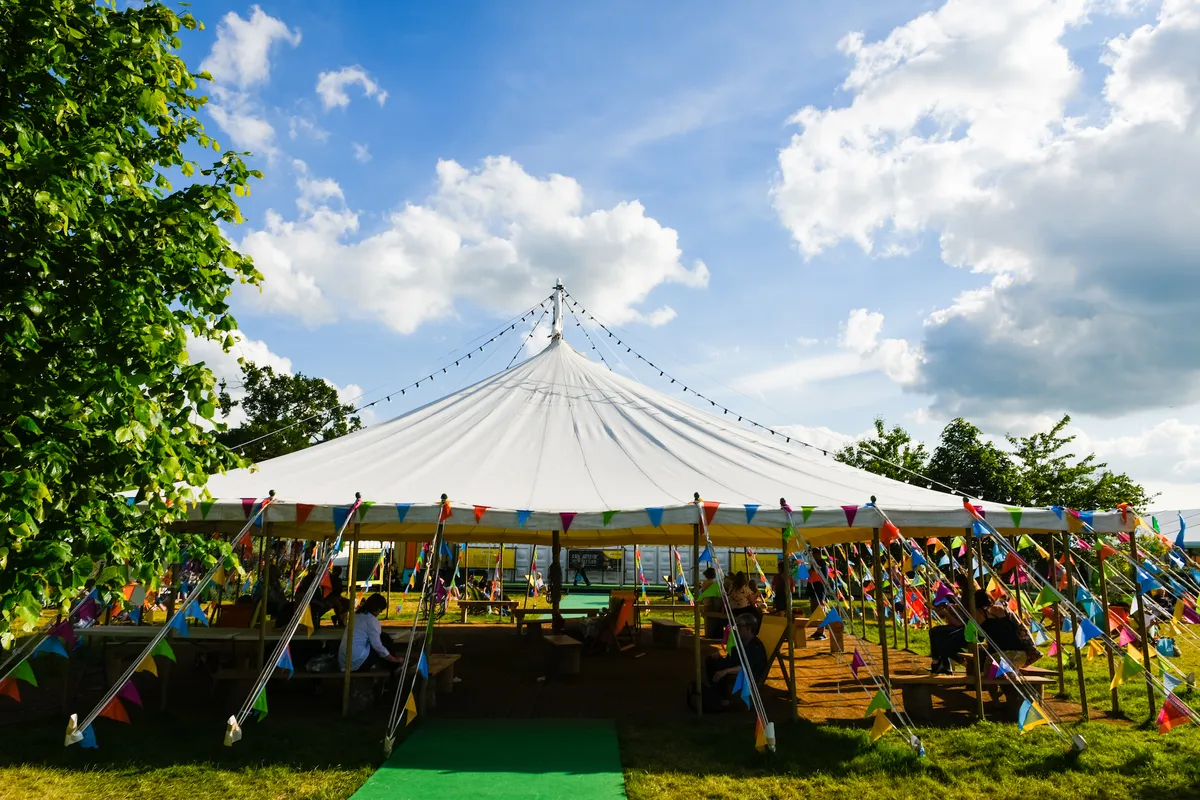 An open-sided tent at the Hay festival, covered in multi-coloured bunting