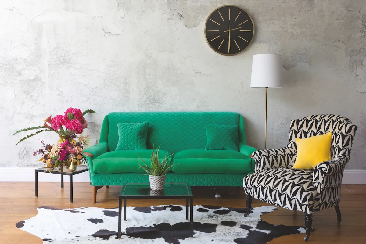 A bright green sofa on a cowhide rug, alongside a geometric print occasional chair.