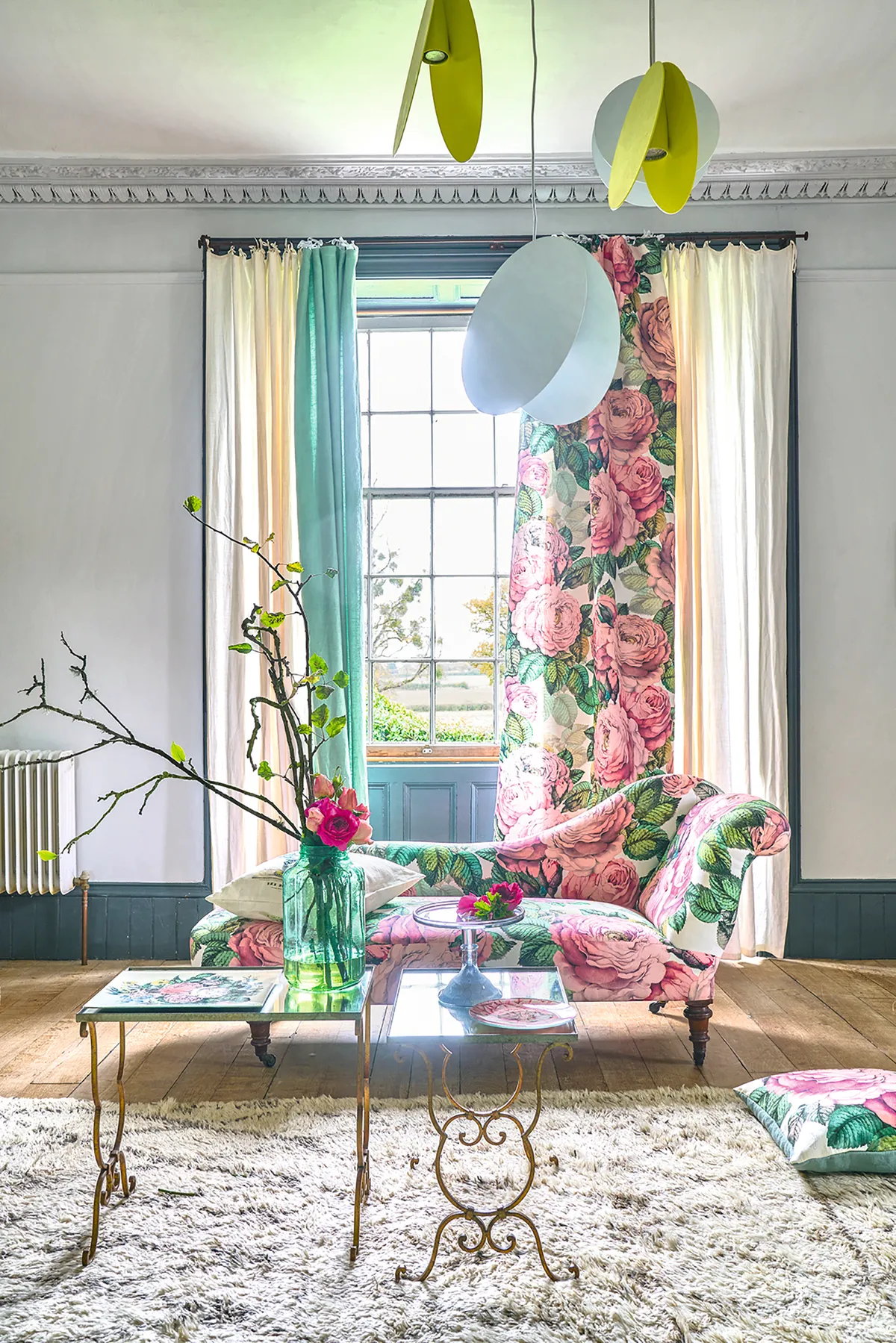 An elegant chaise upholstered in bold pink and green floral fabric.