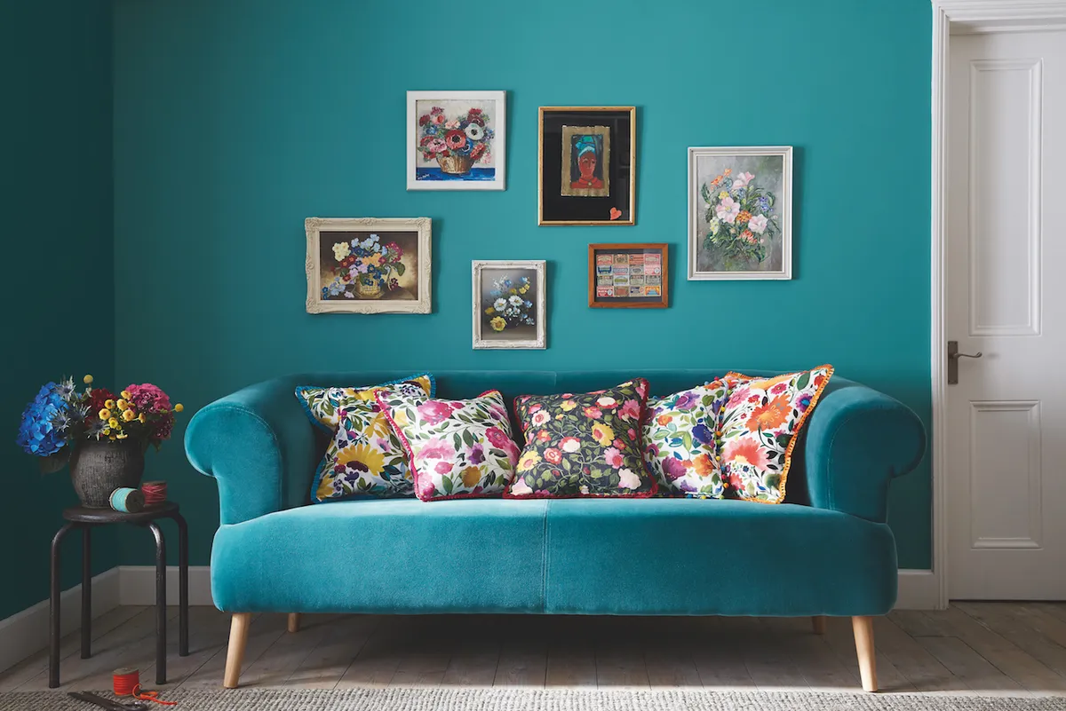 A bright teal sofa in front of a wall of the same colour.