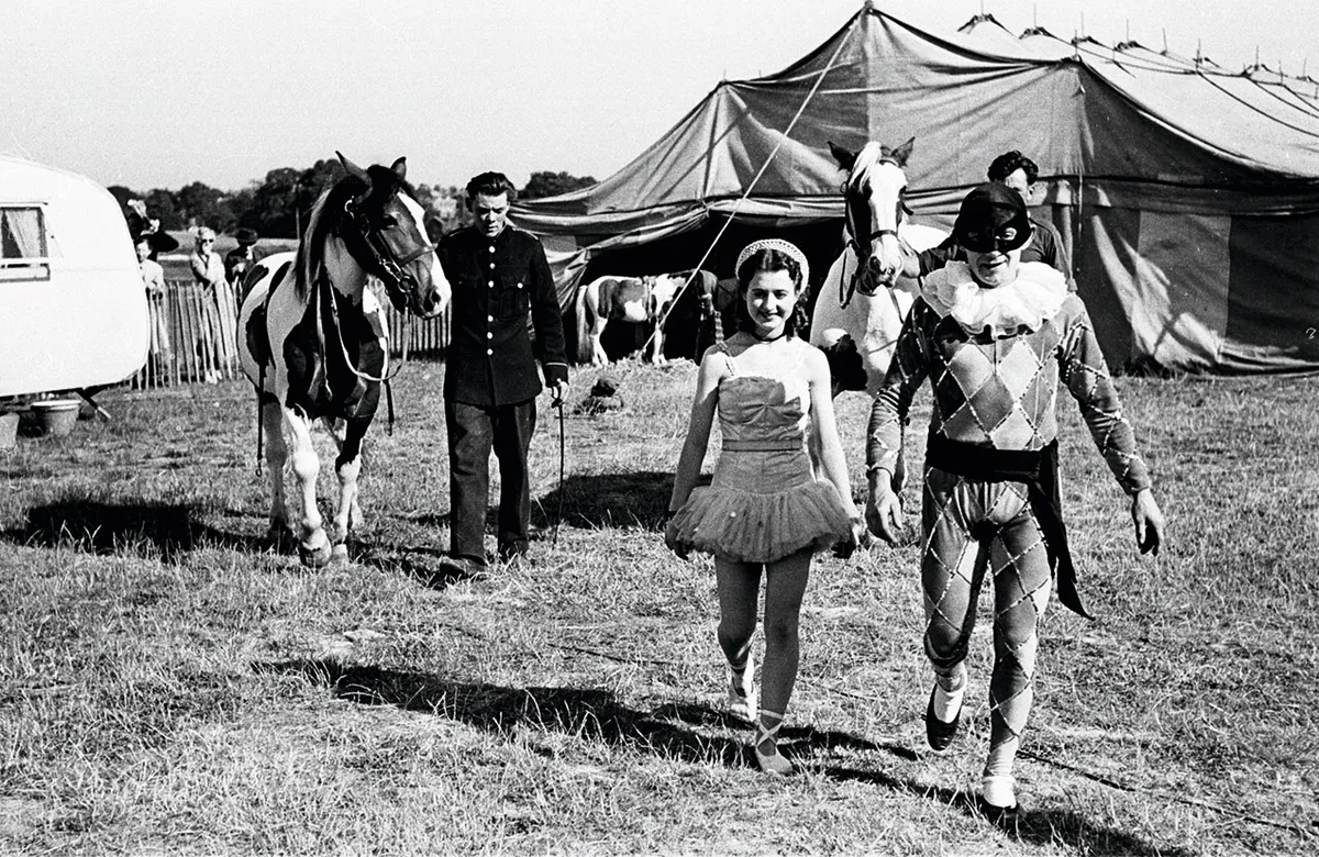 23rd July 1949: Sixteen-year-old Ella Freeman, who performs under the stage name of Ella Clarissa the Ballerina is one of the most popular acts in Lord George Sanger's Circus. Here she approaches the Big Top with her Harlequin partner, prior to a daring two-horse pas-de-deux. Original Publication: Picture Post - 4837 - The Little Circus Queen - pub. 1949 (Photo by Bert Hardy/Picture Post/Getty Images)