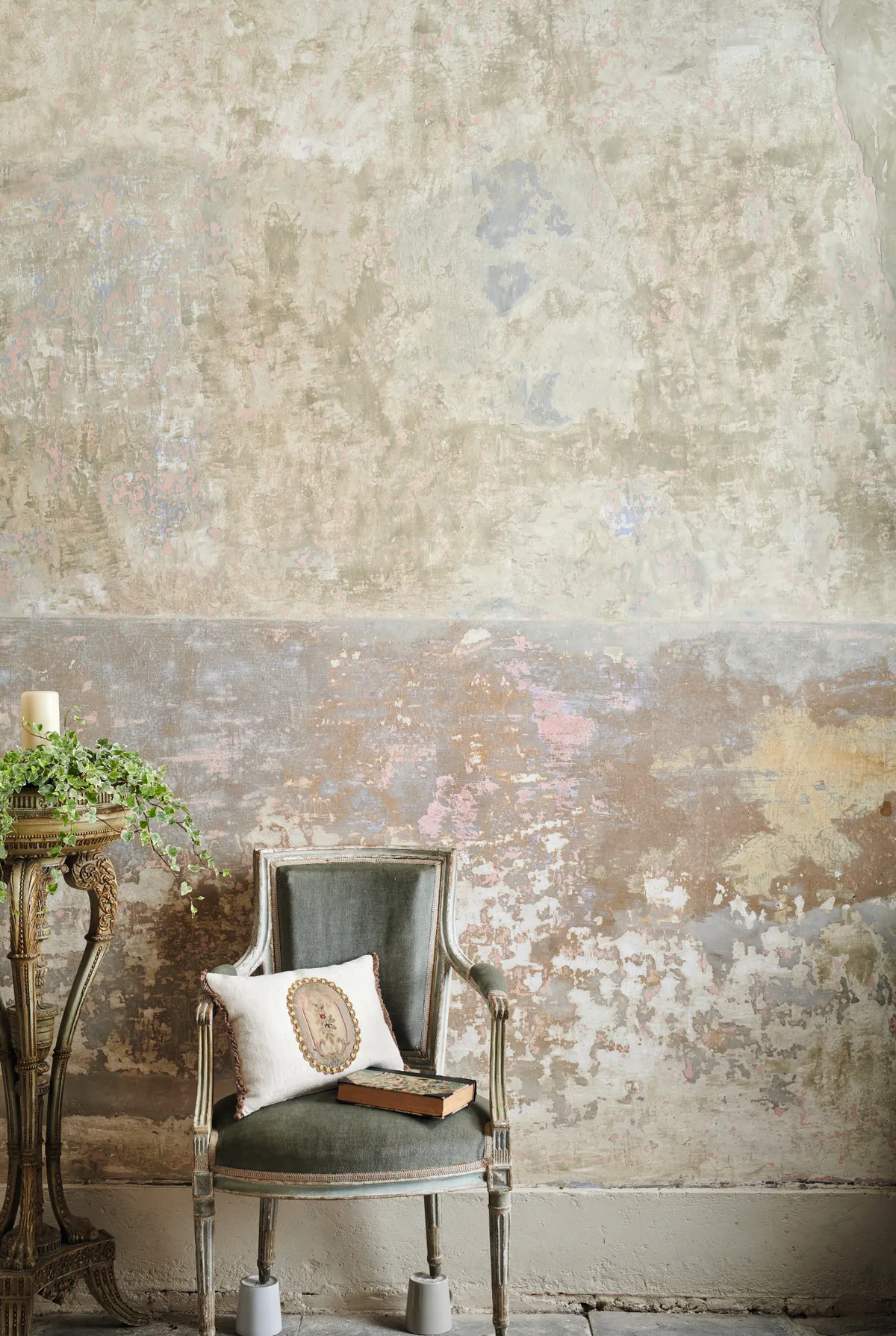 An antique Louis XVI chair in front of a stripped, bare-plaster wall.