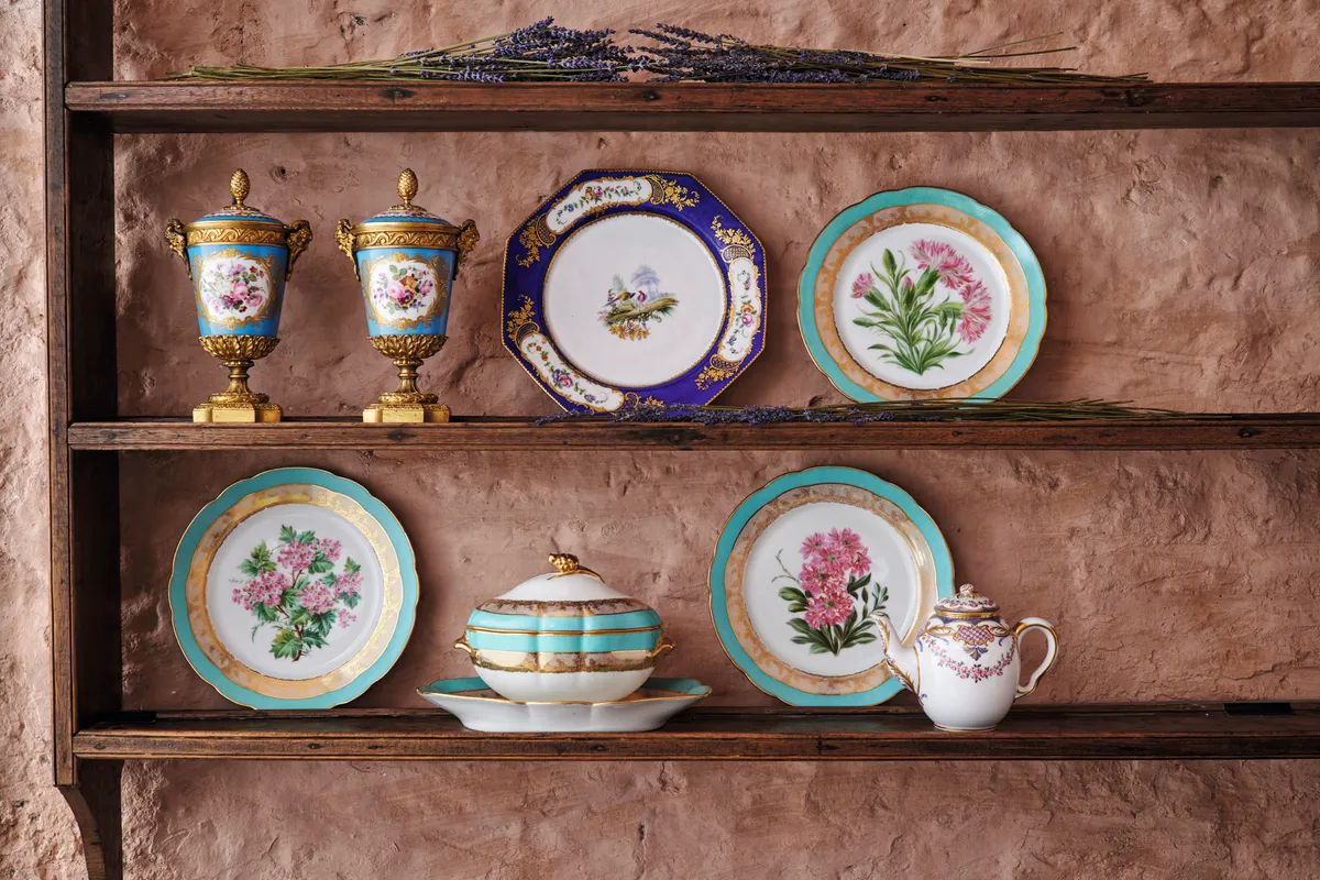 An array of colourful Sevres ceramics displayed on the open shelves of a dresser.
