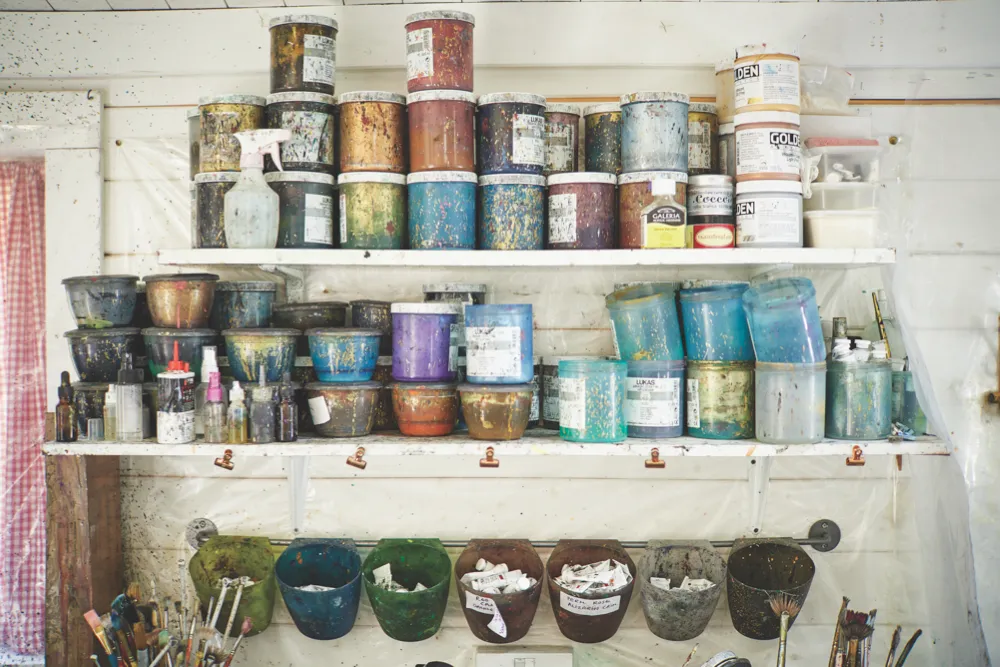The shelves of Jemma's studio piled high with pots of paint and dye