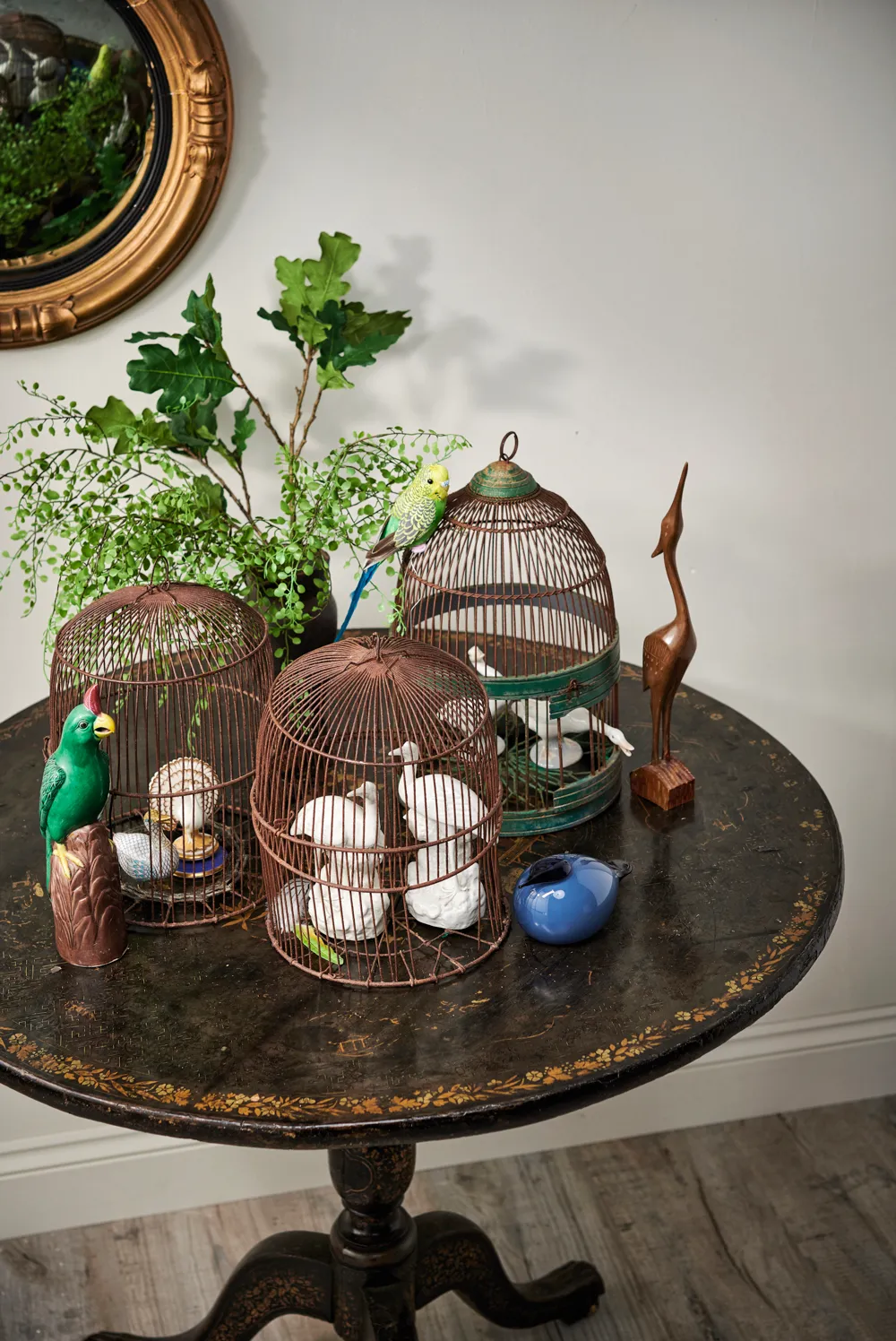 A bird themed eye-catching arrangement on a Regency chinoiserie table. Arrangement includes: 19th century bird cages, 19th century convex mirror