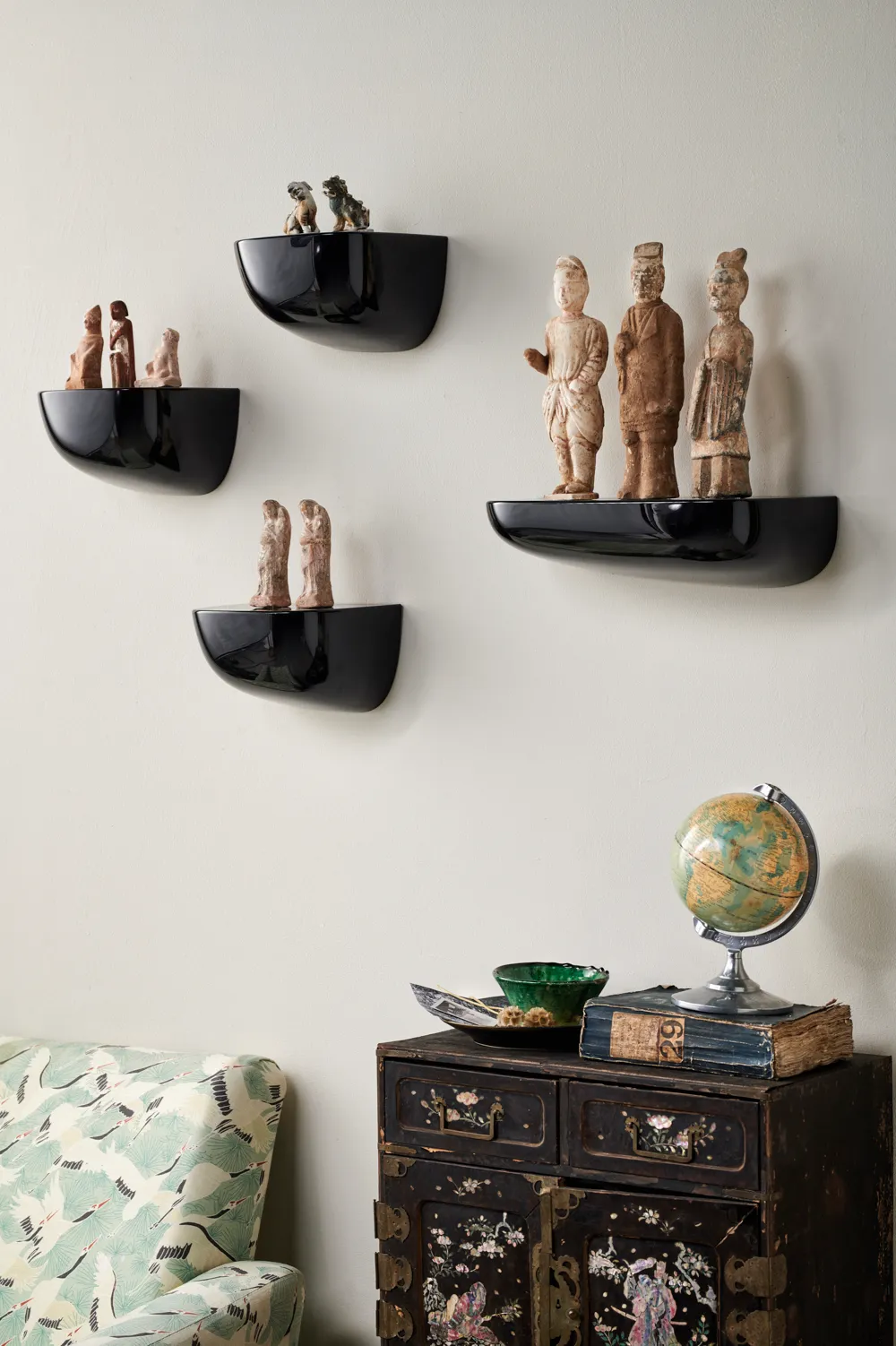 Ancient ornaments displayed on wall-mounted shelves. Modernist cornice shelves. Fragile ancient figures