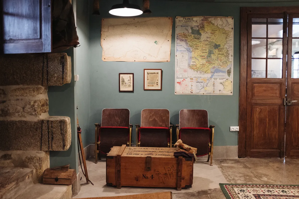 The Boot Room at Chateau de la Motte Husson - painted sage green with a row of vintage cinema seats and an antique chest
