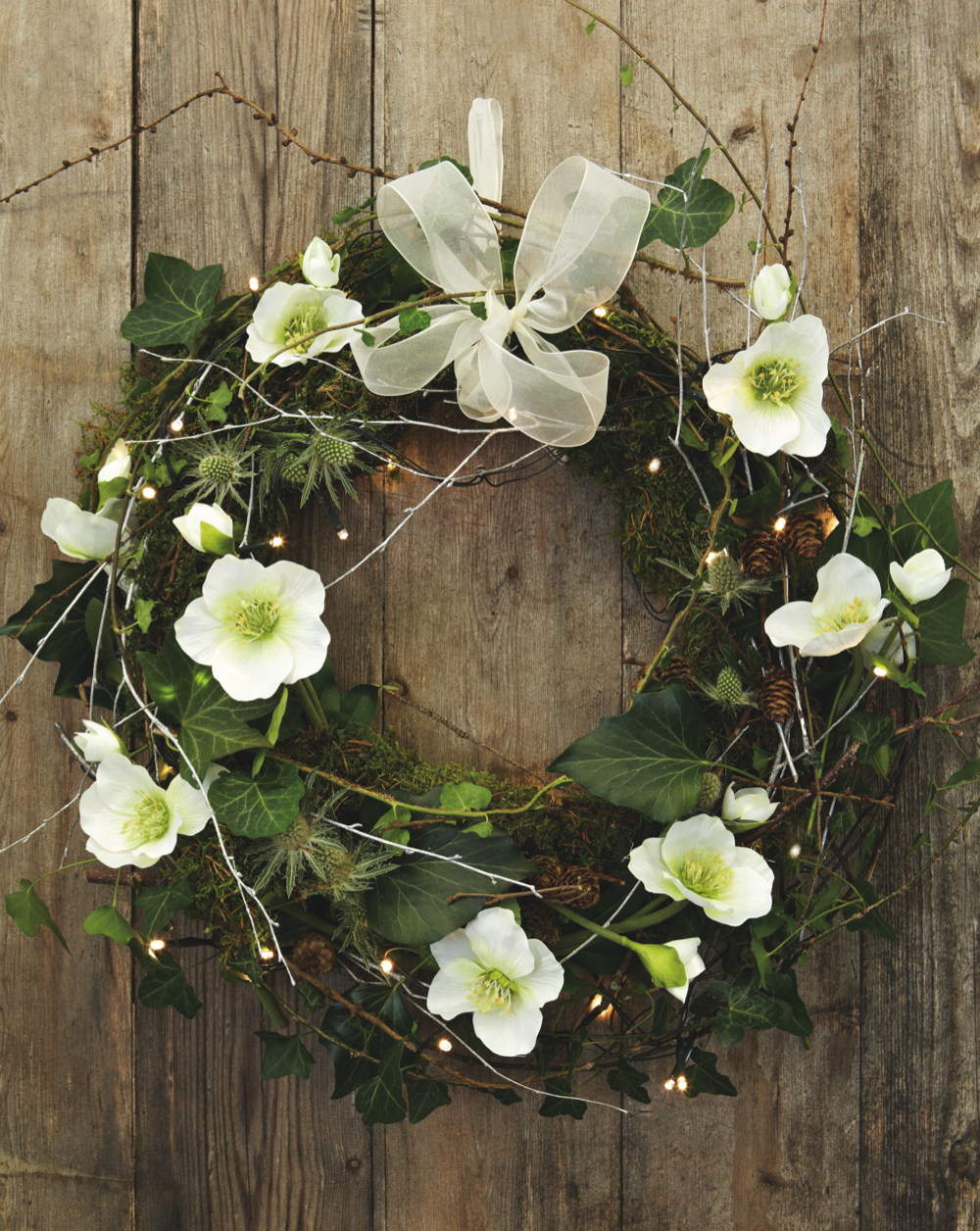 Homemade Christmas wreath with fresh flowers, foraged greenery and white bow