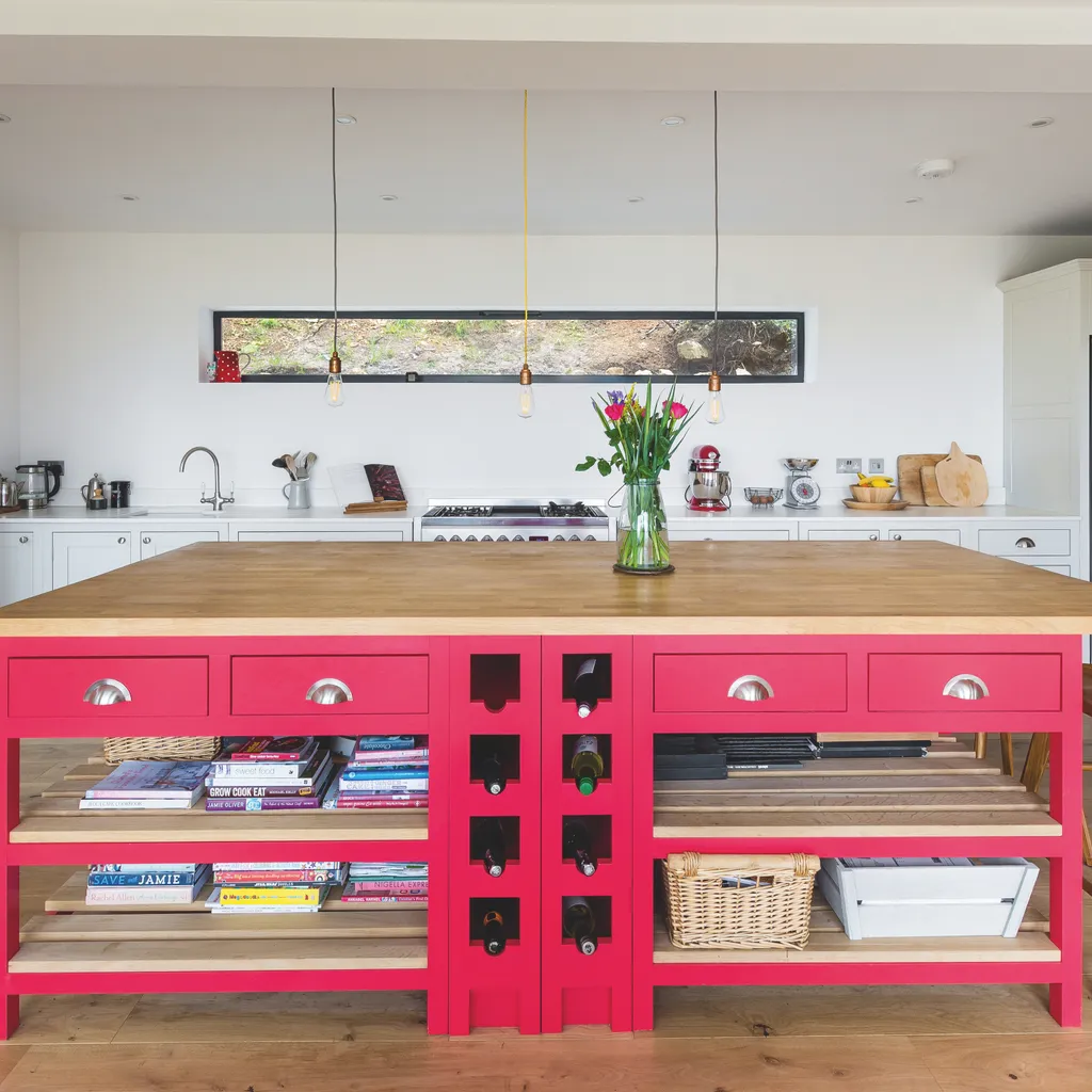A hot pink island with wooden worktop takes centre stage in this kitchen by The Shaker Kitchen Company. Keep walls and fitted units neutral for balance.