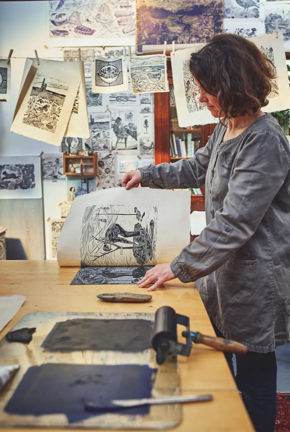 Lou Tonkin peels away paper from the Lino block to show a finished print