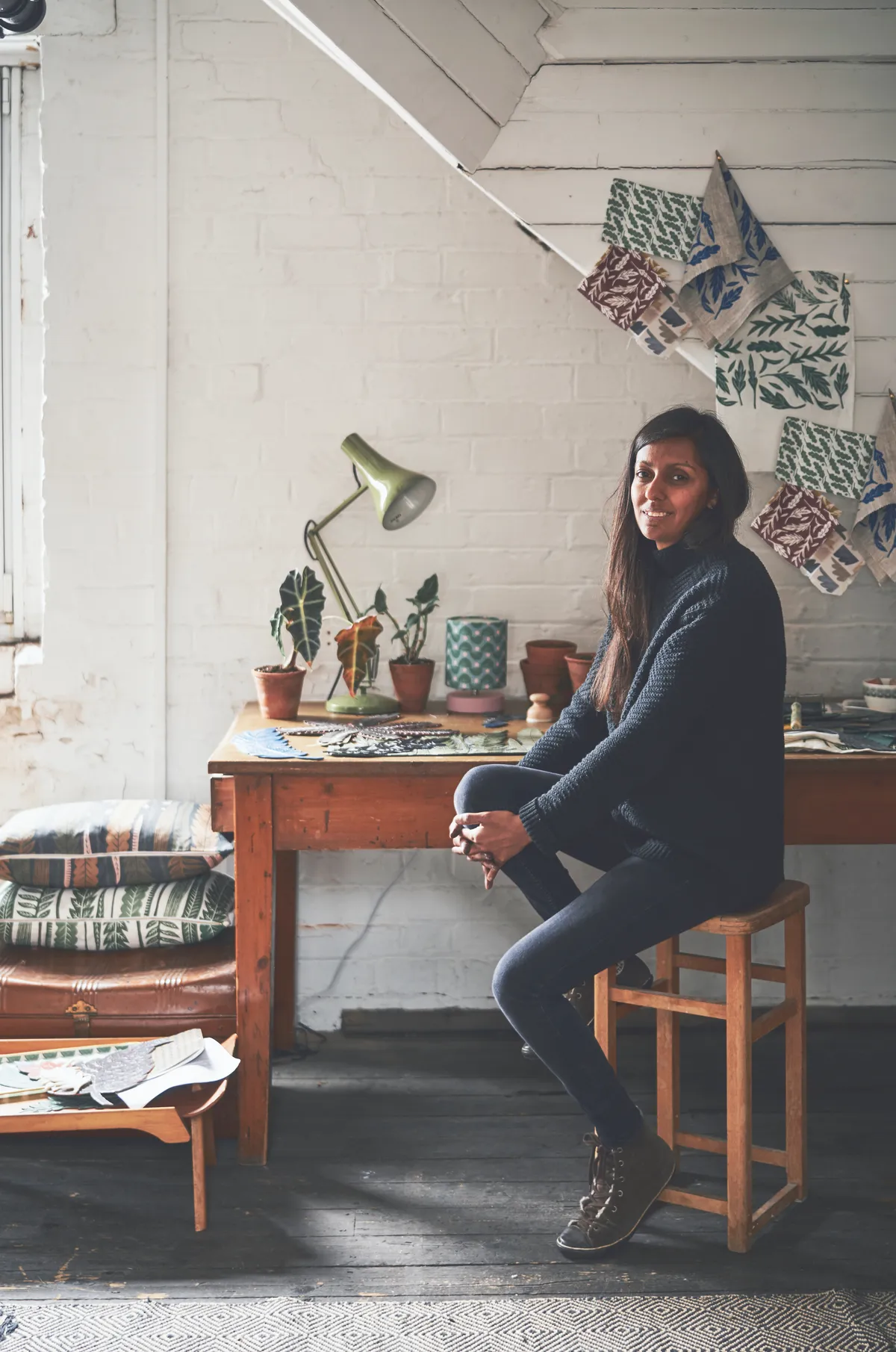 Artist Kiran Ravilious sitting at a vintage desk in her workshop
