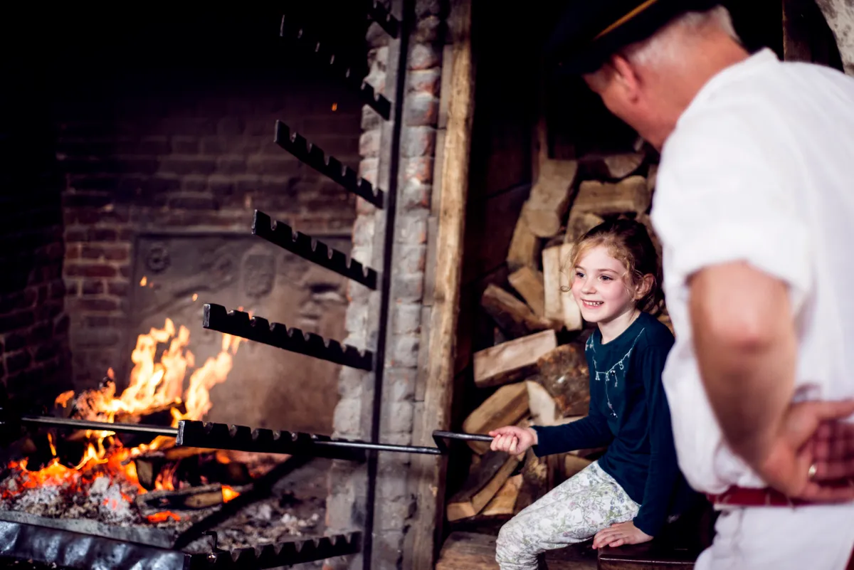 Visitors explore Henry VIII's Kitchens after re-interpretation in 2018. Tudor cooks and kitchen staff show adults and children how the food is made.