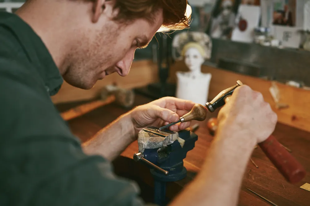 Samuel works on a piece of jewellery in his vice