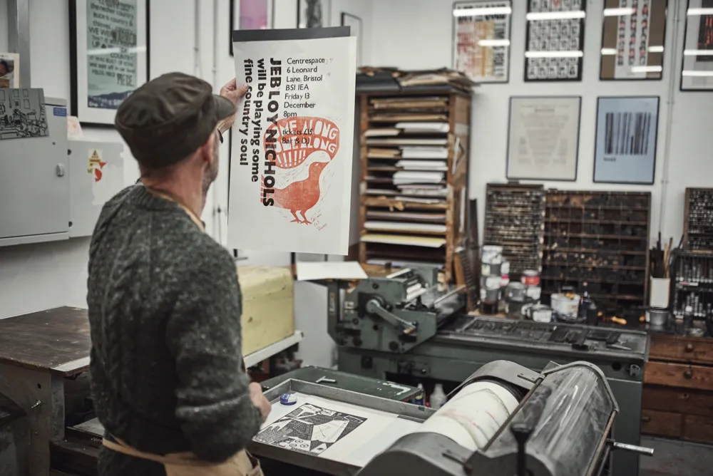 Nick Hand inspects a print that has been put through the press